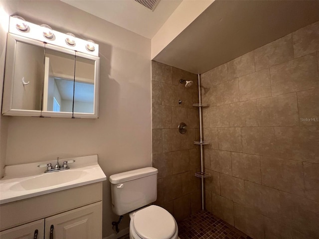 bathroom with a tile shower, vanity, and toilet