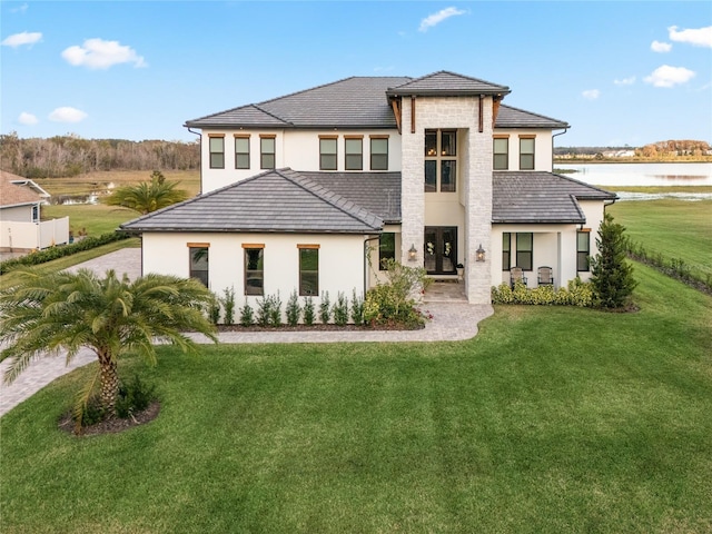 back of property featuring a lawn and a water view