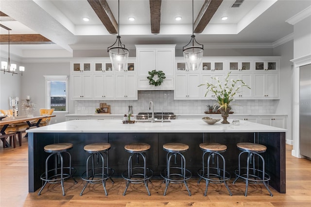 kitchen with beam ceiling, light wood-type flooring, a spacious island, and sink