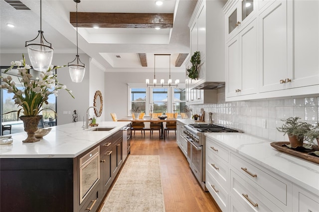 kitchen with high end stove, white cabinetry, and hanging light fixtures