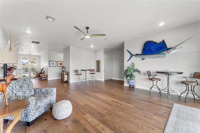 living room with hardwood / wood-style flooring and ceiling fan with notable chandelier