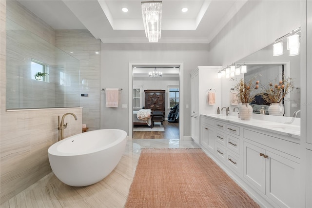 bathroom with vanity, a tray ceiling, wood-type flooring, tile walls, and a notable chandelier