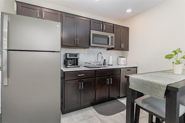 kitchen featuring decorative backsplash, dark brown cabinetry, stainless steel appliances, sink, and light tile patterned flooring