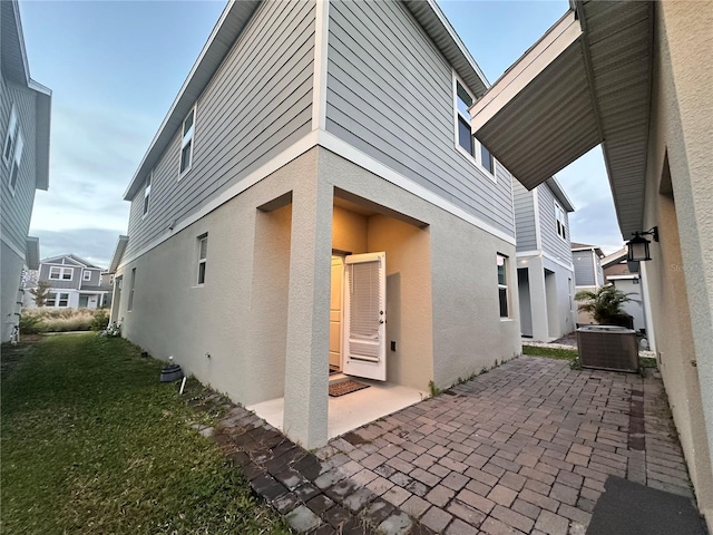 view of side of property featuring a patio, cooling unit, and a lawn