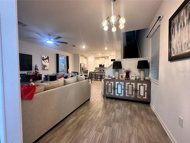 living room with hardwood / wood-style flooring and ceiling fan with notable chandelier