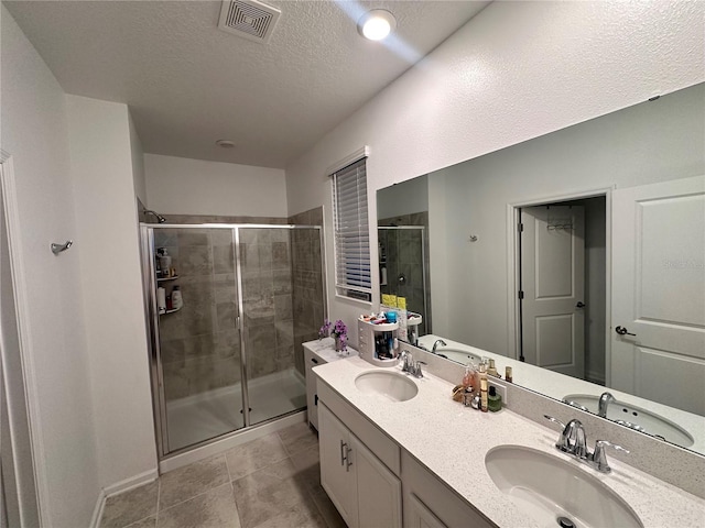 bathroom featuring a textured ceiling, vanity, tile patterned floors, and a shower with shower door