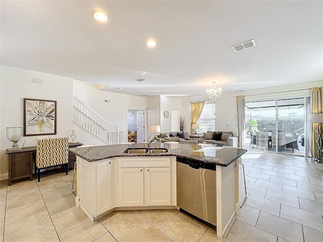 kitchen with dishwasher, sink, dark stone countertops, an island with sink, and white cabinets