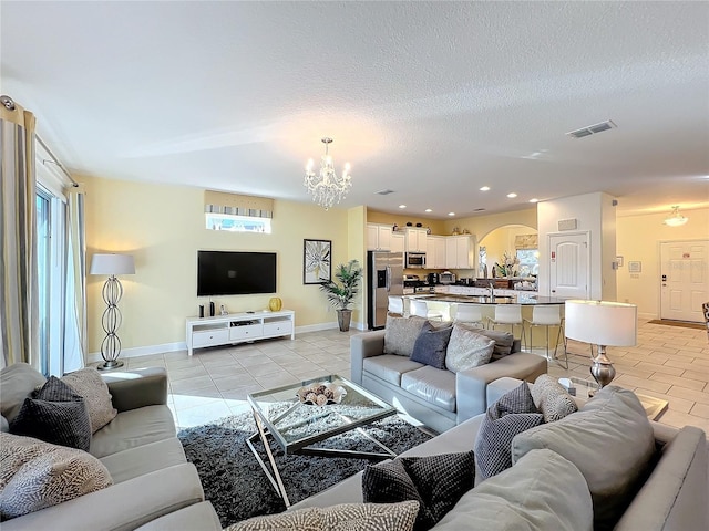 living room with plenty of natural light, light tile patterned floors, a textured ceiling, and a chandelier