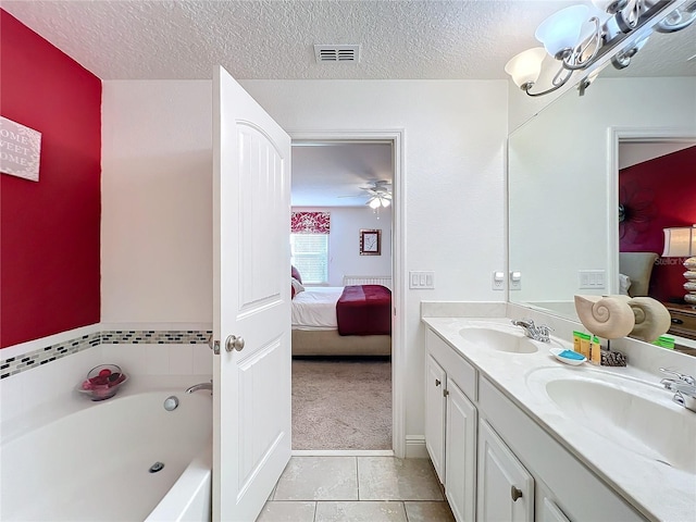 bathroom featuring a tub to relax in, a textured ceiling, vanity, ceiling fan, and tile patterned flooring