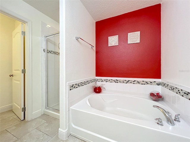 bathroom with tile patterned flooring, shower with separate bathtub, and a textured ceiling