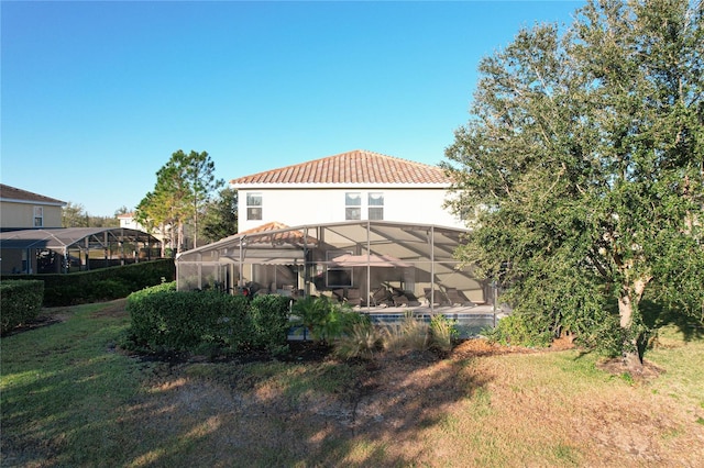 back of property featuring glass enclosure and a yard