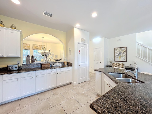 kitchen with sink, hanging light fixtures, dark stone countertops, a chandelier, and white cabinets