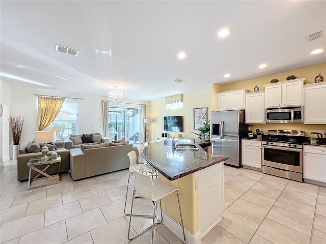 kitchen featuring sink, stainless steel appliances, a breakfast bar area, a kitchen island with sink, and white cabinets