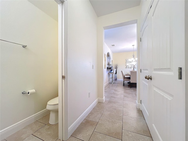 hallway featuring light tile patterned floors and an inviting chandelier