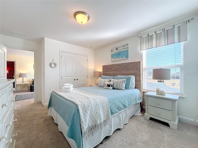 carpeted bedroom with a textured ceiling and a closet