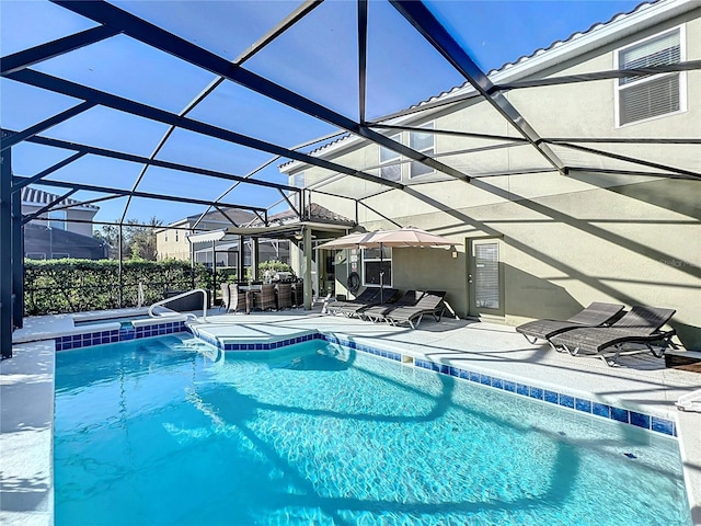 view of pool with glass enclosure, a patio area, exterior bar, and a hot tub