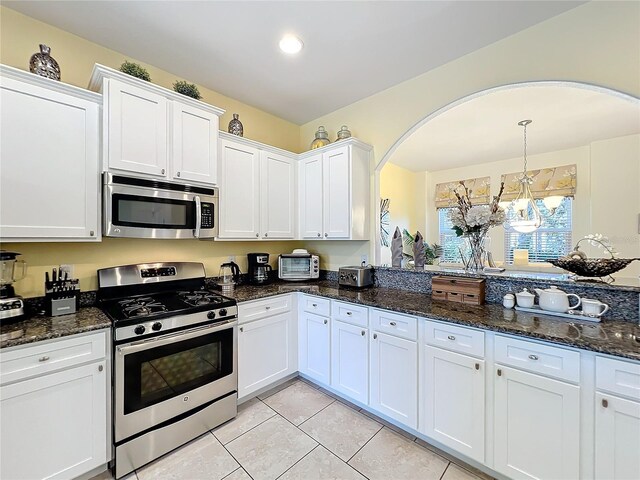 kitchen featuring appliances with stainless steel finishes, light tile patterned floors, an inviting chandelier, white cabinetry, and hanging light fixtures