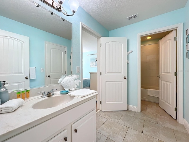 bathroom with vanity, tiled shower / bath combo, and a textured ceiling