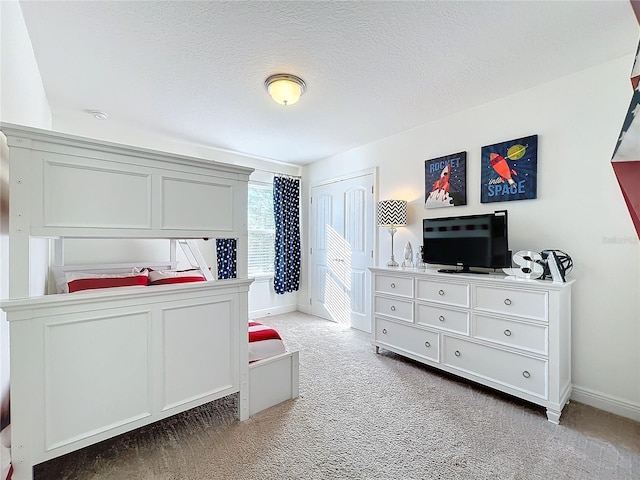 carpeted bedroom featuring baseboards and a textured ceiling