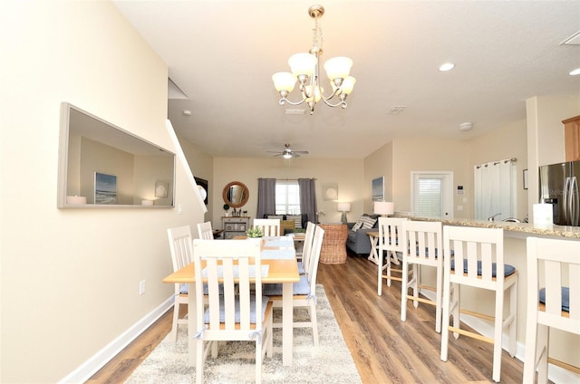 dining area featuring ceiling fan with notable chandelier and light hardwood / wood-style floors