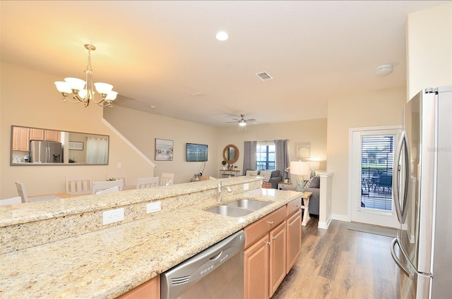 kitchen featuring a breakfast bar, ceiling fan with notable chandelier, sink, wood-type flooring, and stainless steel appliances