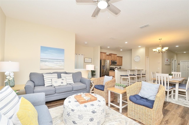 living room featuring ceiling fan with notable chandelier and hardwood / wood-style flooring