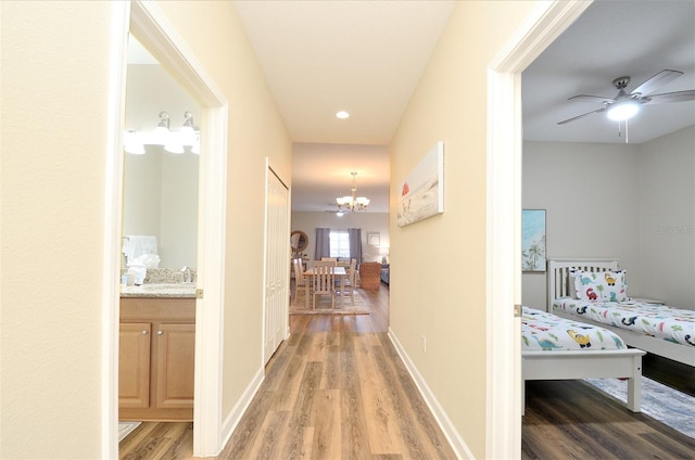 corridor with wood-type flooring and a notable chandelier