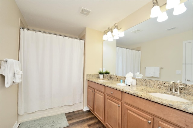 bathroom featuring hardwood / wood-style flooring, vanity, shower / bath combo with shower curtain, and a chandelier