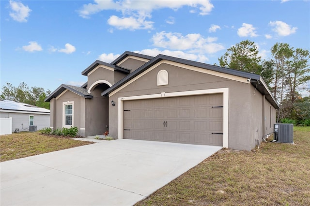 ranch-style house featuring cooling unit, a front yard, and a garage