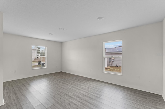 unfurnished room with light hardwood / wood-style floors, a textured ceiling, and a wealth of natural light