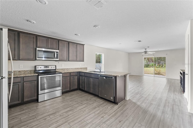 kitchen featuring kitchen peninsula, appliances with stainless steel finishes, a textured ceiling, ceiling fan, and light hardwood / wood-style flooring