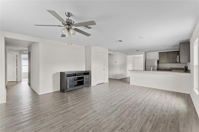 unfurnished living room with ceiling fan and light wood-type flooring