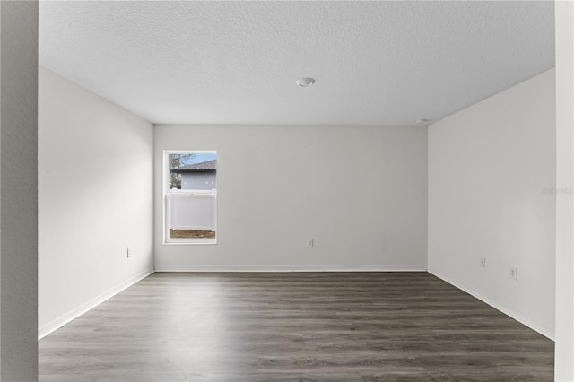 spare room featuring dark hardwood / wood-style flooring and a textured ceiling