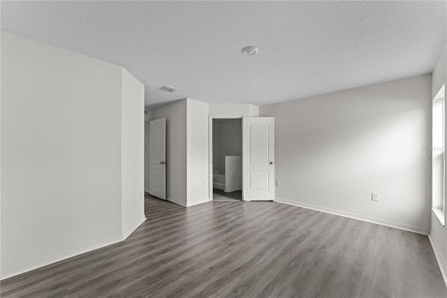 unfurnished room with a textured ceiling and dark wood-type flooring