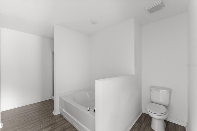 bathroom with hardwood / wood-style floors, a bathtub, and toilet