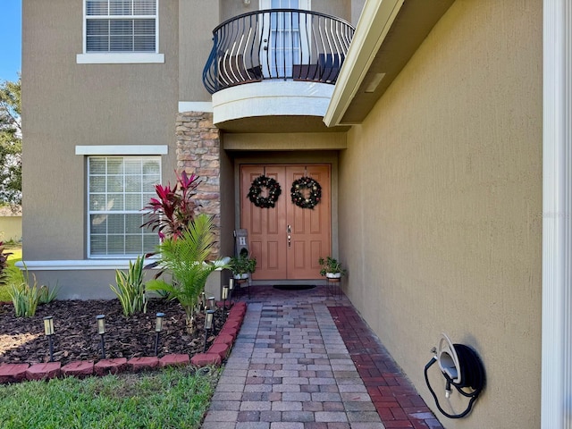 view of exterior entry with a balcony