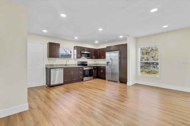 kitchen with appliances with stainless steel finishes, light hardwood / wood-style flooring, plenty of natural light, and sink