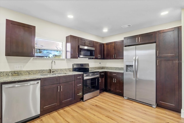 kitchen featuring sink, light wood-type flooring, dark brown cabinets, light stone counters, and stainless steel appliances