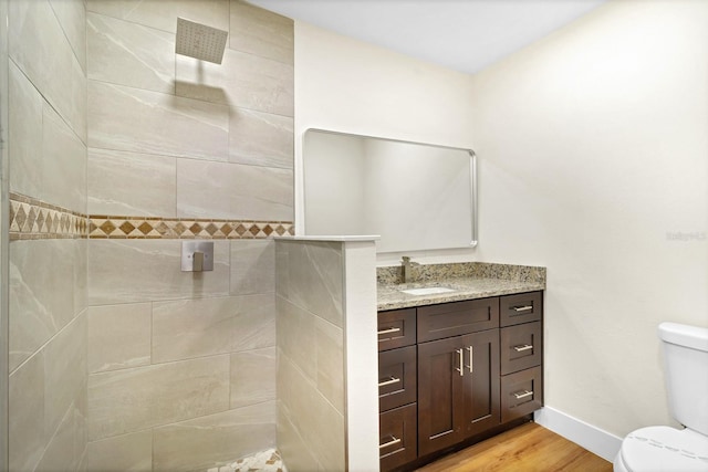 bathroom with vanity, toilet, wood-type flooring, and tiled shower