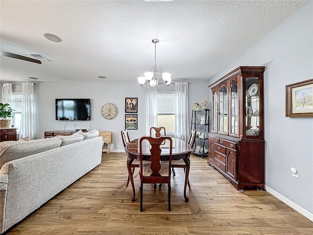 dining area with a chandelier, a textured ceiling, and light wood-type flooring