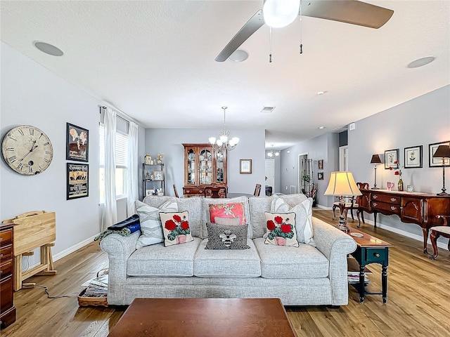 living room with ceiling fan with notable chandelier and hardwood / wood-style flooring