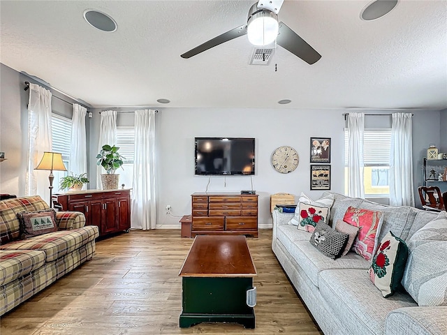 living room with ceiling fan, wood-type flooring, and a textured ceiling