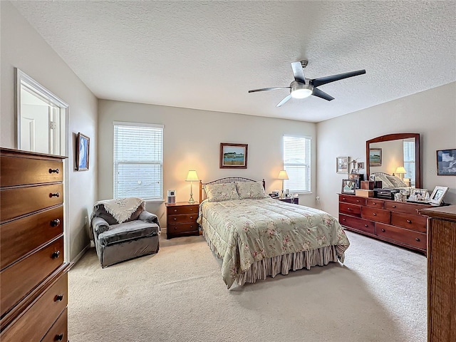 bedroom with ceiling fan, light carpet, and a textured ceiling