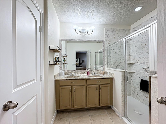 bathroom with tile patterned flooring, a chandelier, a textured ceiling, a shower with door, and vanity