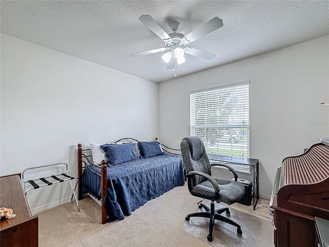 bedroom featuring ceiling fan, light colored carpet, and a textured ceiling