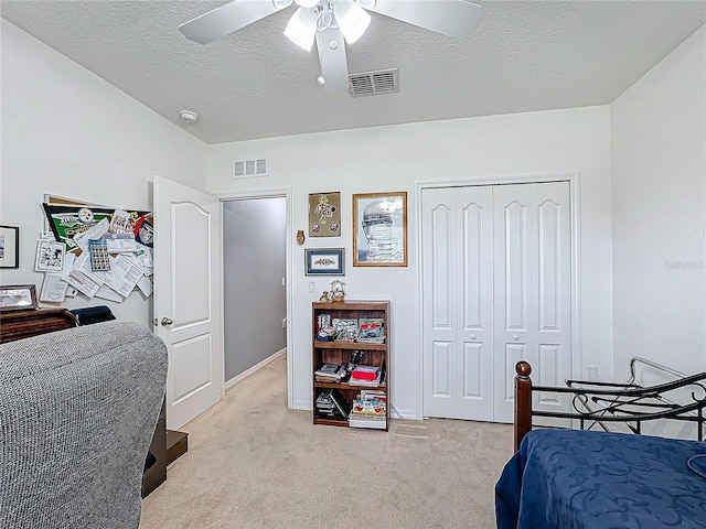 bedroom featuring light carpet, a textured ceiling, a closet, and ceiling fan