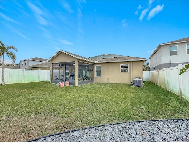 back of property with a sunroom, a yard, and central AC