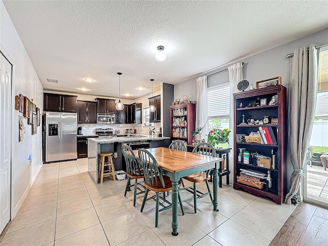 dining room with light tile patterned floors, a textured ceiling, and a wealth of natural light