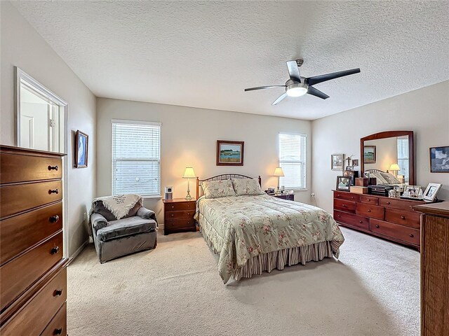 bedroom featuring light carpet, a textured ceiling, and ceiling fan