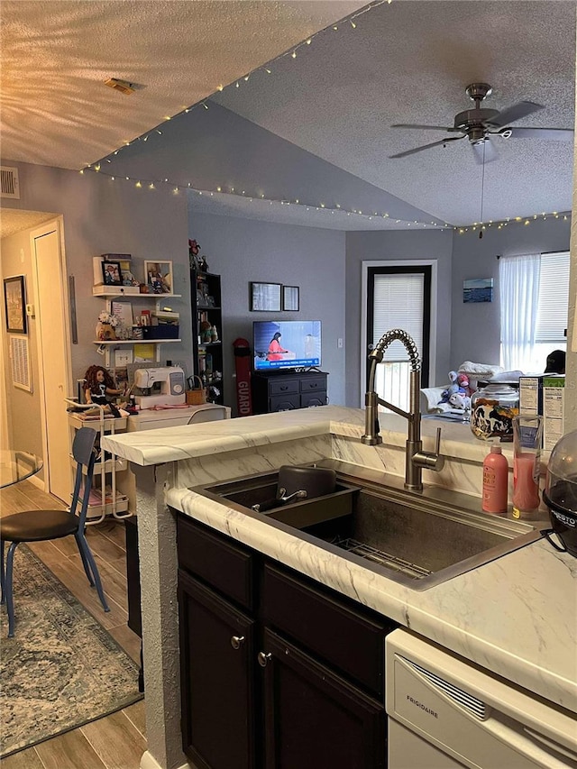 kitchen with dishwasher, sink, light hardwood / wood-style floors, a textured ceiling, and vaulted ceiling